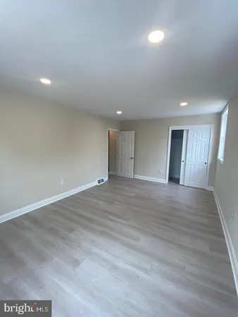 a view of an empty room with wooden floor and closet