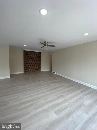 an empty room with wooden floor and kitchen view