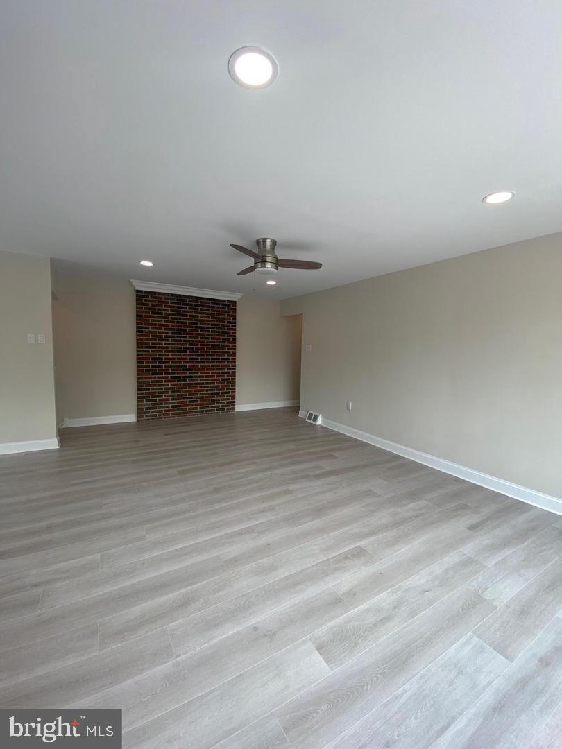 1207 County Line Road Bryn Mawr, PA 19010 - Photo 3 of 17 an empty room with wooden floor and kitchen view