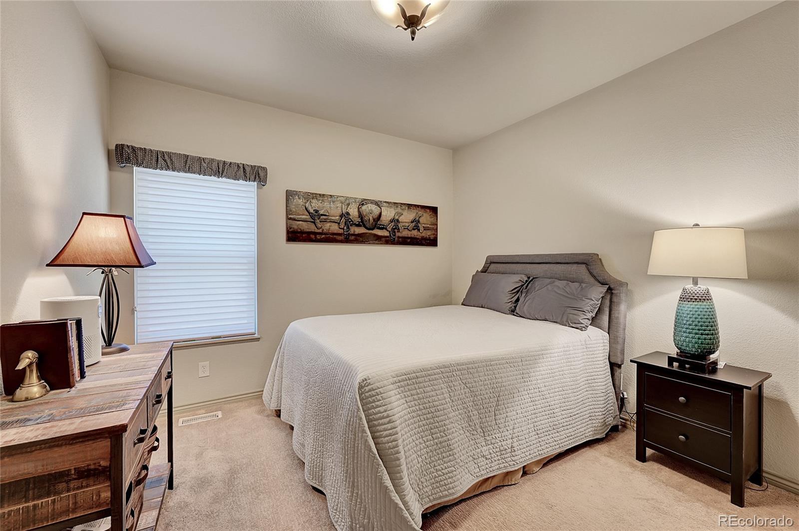 11232 West Cooper Drive Littleton, CO 80127 - Photo 24 of 48 a bedroom with a bed and a lamp on table