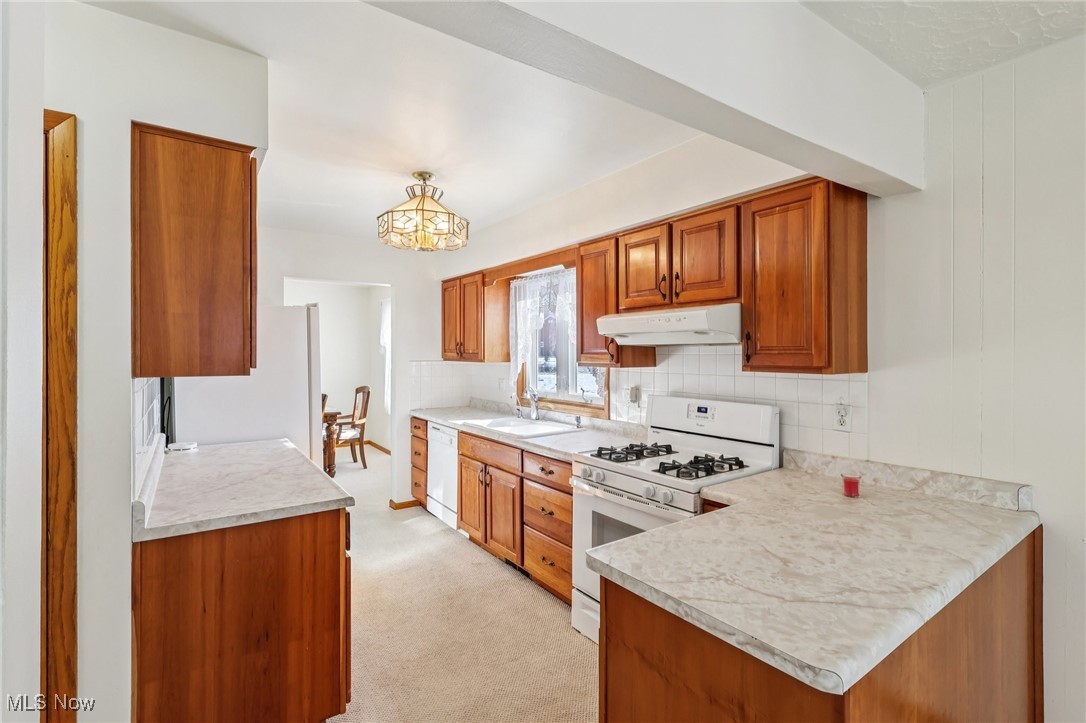 970 Eastern Road Doylestown, OH 44230 - Photo 10 of 49 Kitchen with brown cabinets, white appliances, light countertops, light colored carpet, and a peninsula