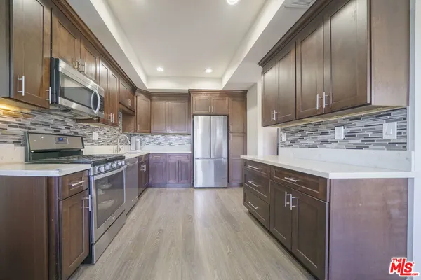 a kitchen with stainless steel appliances granite countertop wooden cabinets a sink and dishwasher a stove top oven with wooden floor