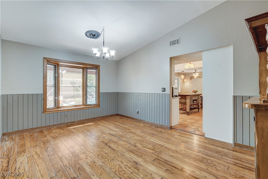 845 Robinson Lane Boulder City, NV 89005 - Photo 20 of 66 Unfurnished dining area featuring vaulted ceiling, wood-type flooring, wainscoting, and a chandelier