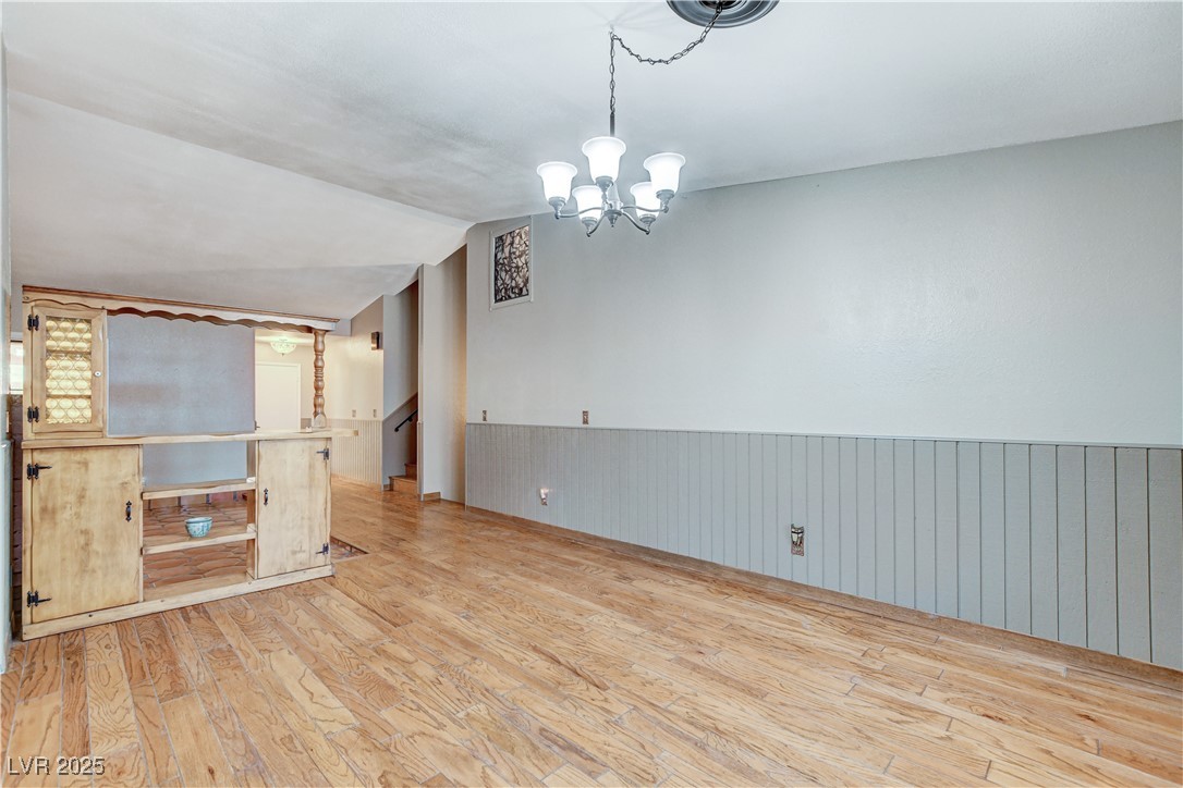845 Robinson Lane Boulder City, NV 89005 - Photo 22 of 66 Unfurnished room featuring wainscoting, wood finished floors, a chandelier, and lofted ceiling