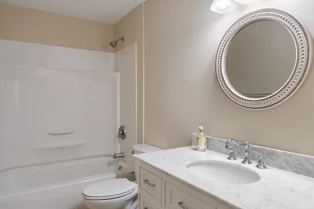 a bathroom with a granite countertop toilet a sink and a mirror