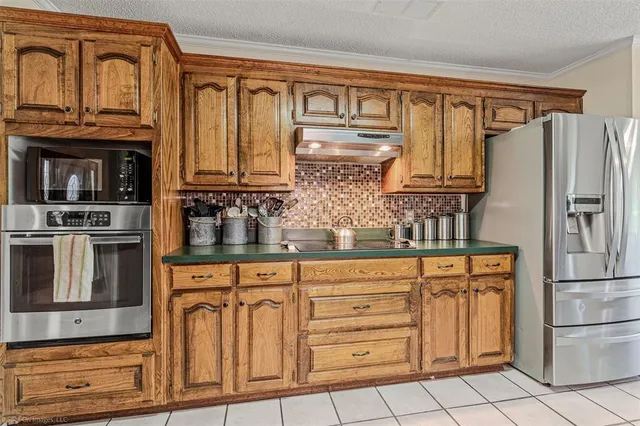 a kitchen with granite countertop a refrigerator stove and cabinets
