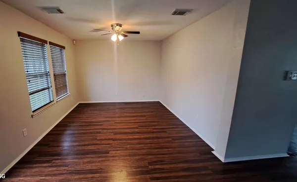 a view of an empty room with wooden floor and a window
