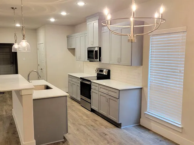 a kitchen that has a sink a stove and a wooden floor