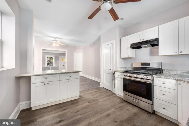 a kitchen with stainless steel appliances white cabinets and wooden floors