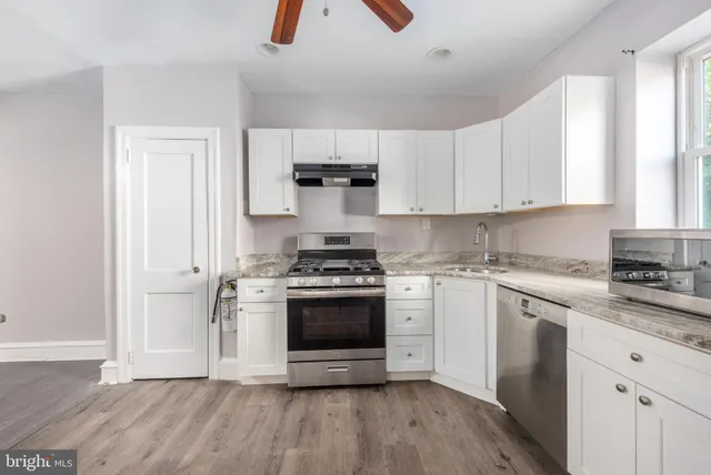 a kitchen with cabinets stainless steel appliances a sink and wooden floor