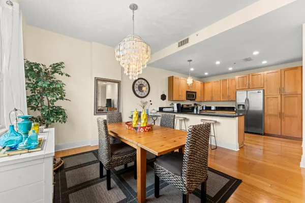 a view of a dining room and kitchen with furniture a chandelier and wooden floor