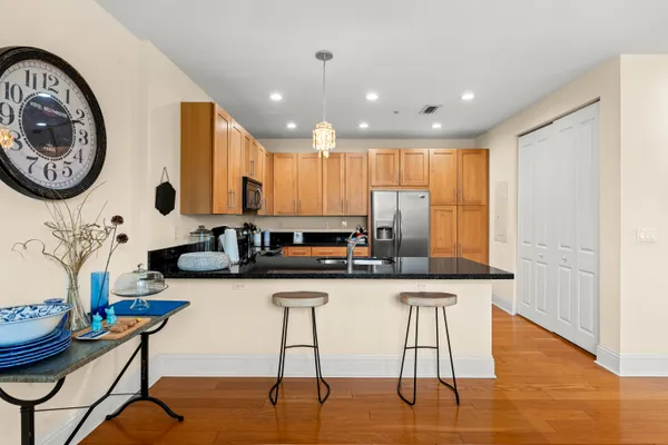a kitchen with stainless steel appliances granite countertop a table chairs in it and wooden floors