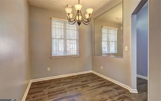 a view of empty room with wooden floor and chandelier