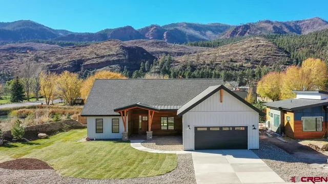 a front view of a house with a yard and mountain view