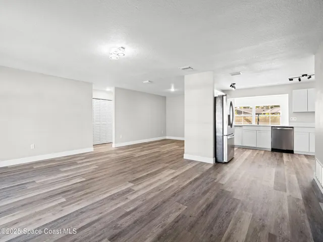 a view of a big room with wooden floor and windows
