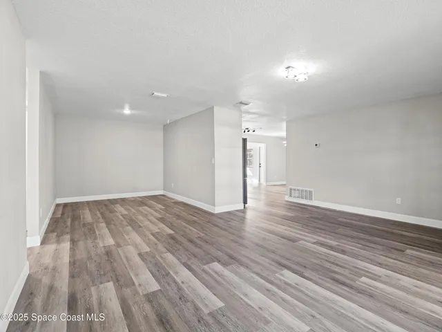 a view of empty room with wooden floor