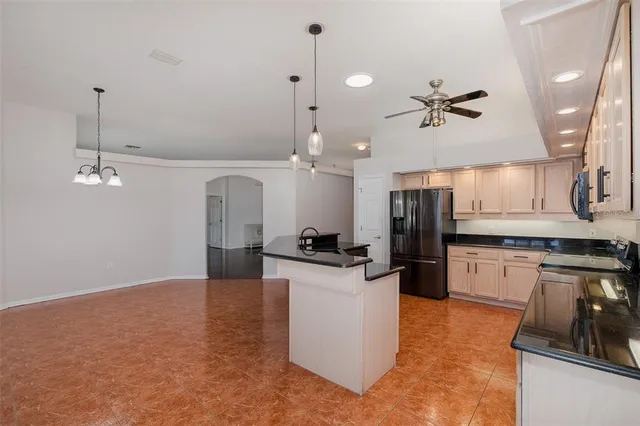 a kitchen with stainless steel appliances granite countertop a sink a refrigerator a center island a stove and a wooden floor