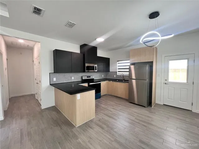 a kitchen with granite countertop a refrigerator a stove top oven a sink and wooden floor