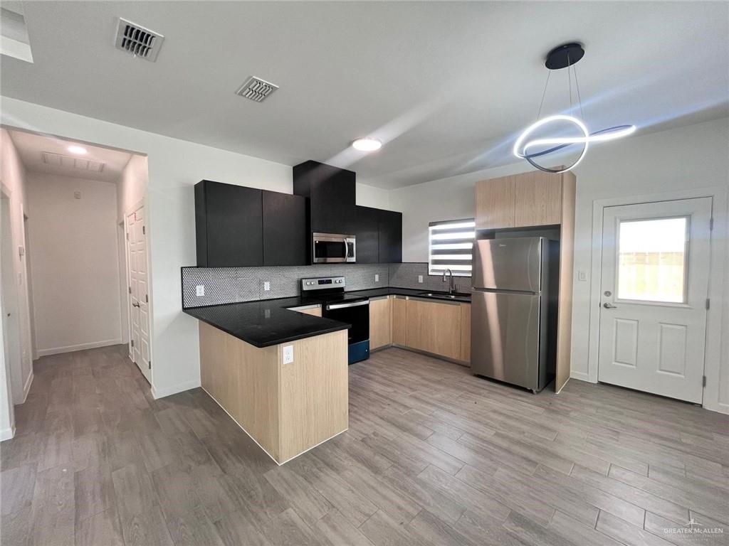 3900 Ventura Avenue, Unit 3 Edinburg, TX 78541 - Photo 12 of 14 a kitchen with granite countertop a refrigerator a stove top oven a sink and wooden floor