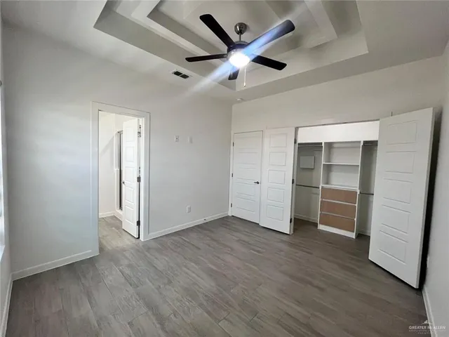 an empty room with wooden floor and a ceiling fan