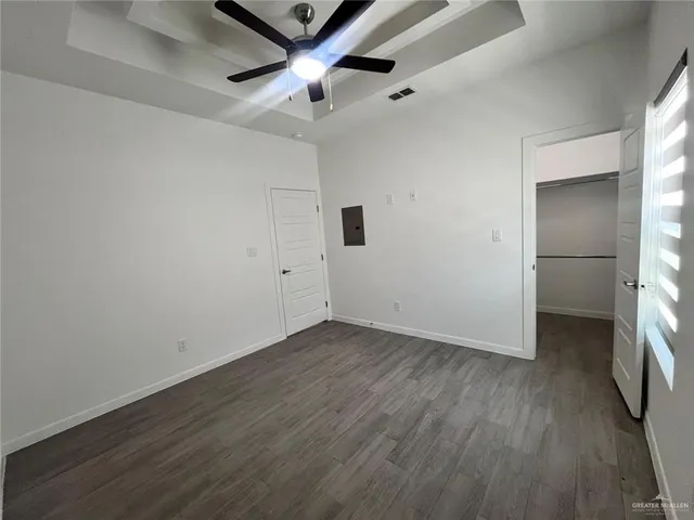 an empty room with wooden floor and a ceiling fan