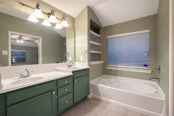 a bathroom with a tub a sink double vanity and a mirror