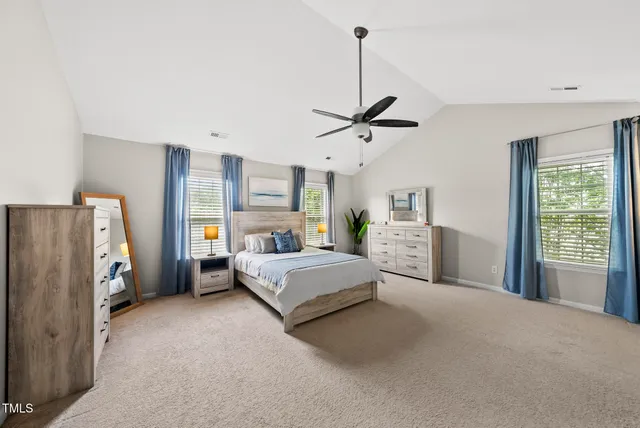 a spacious bedroom with a bed windows and cabinet