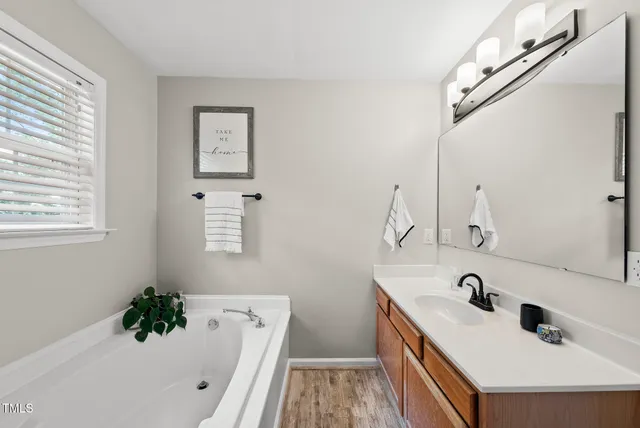 a bathroom with a tub sink and mirror
