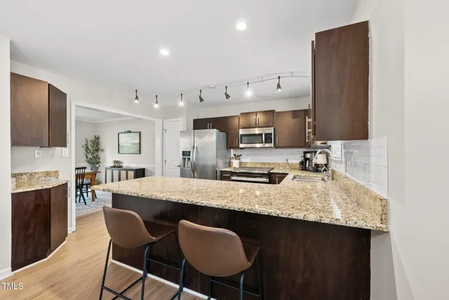 a kitchen with stainless steel appliances granite countertop a stove top oven a sink dishwasher and a refrigerator with wooden floor