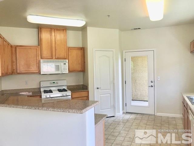 9050 Double R Boulevard, Unit 1125 Reno, NV 89511 - Photo 3 of 24 a kitchen with granite countertop a refrigerator a sink and a stove top oven