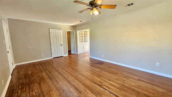 a view of a room with wooden floor and a ceiling fan