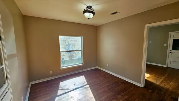 an empty room with wooden floor cabinet and windows