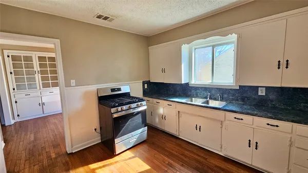 a kitchen with granite countertop a stove a sink and a microwave