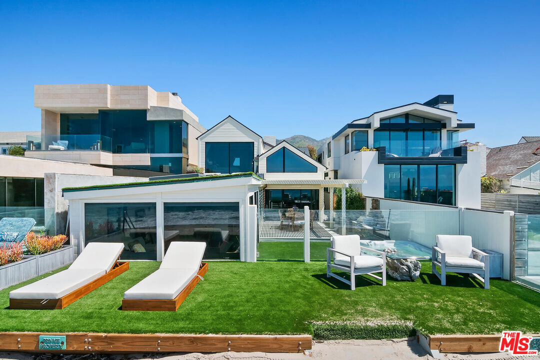 107 Malibu Colony Road Malibu, CA 90265 - Photo 2 of 12 a front view of a house with a yard table and chairs