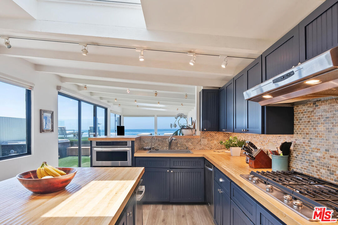 107 Malibu Colony Road Malibu, CA 90265 - Photo 3 of 12 a kitchen with stainless steel appliances granite countertop a sink stove and wooden cabinets
