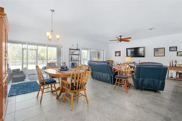 a view of a dining room and livingroom with furniture wooden floor a rug a flat screen tv a rug and a chandelier