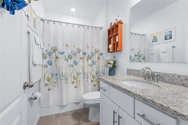 a bathroom with a granite countertop sink a toilet and shower curtain