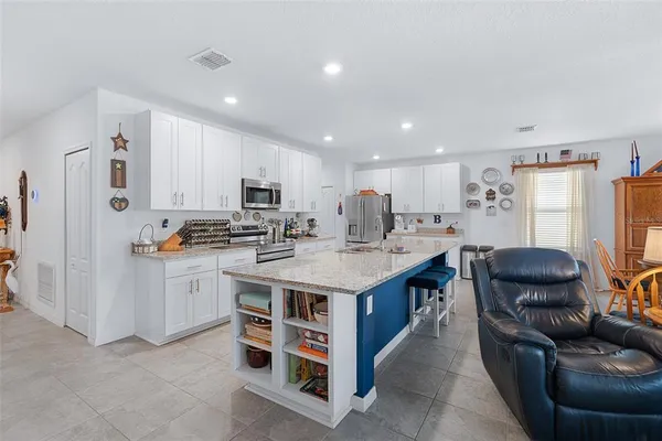 a kitchen with stainless steel appliances kitchen island granite countertop a table chairs and a refrigerator