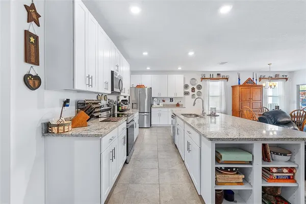 a large white kitchen with stainless steel appliances granite countertop a lot of counter space and wooden floor