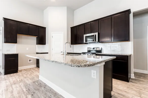a kitchen with granite countertop a refrigerator and a stove top oven