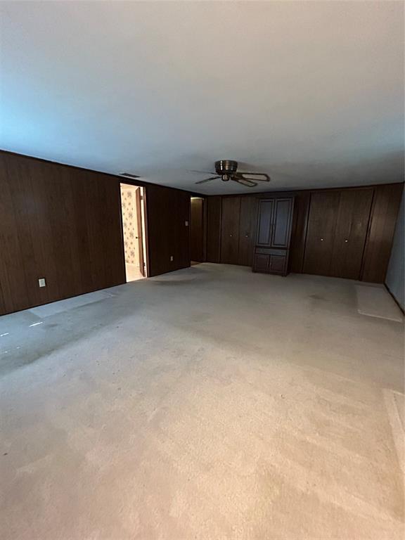 241 Aurora Street Rhome, TX 76078 - Photo 16 of 28 Master bedroom featuring light colored carpet, wooden walls, and ceiling fan
