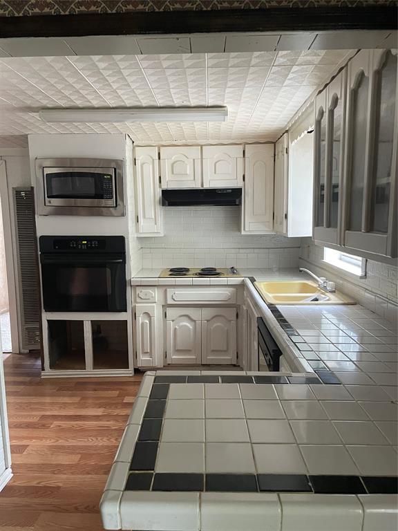 241 Aurora Street Rhome, TX 76078 - Photo 19 of 28 Kitchen with tile counters, wall oven, electric stovetop, and backsplash