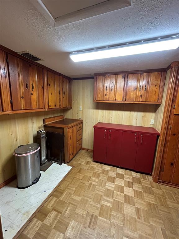 241 Aurora Street Rhome, TX 76078 - Photo 10 of 28 Kitchen with wooden walls, a textured ceiling, brown cabinetry, and light flooring