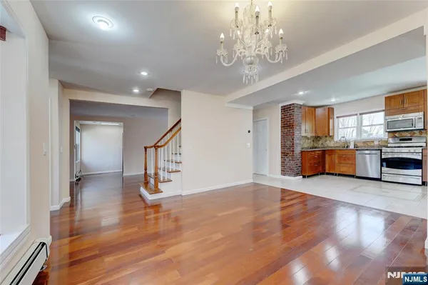a view of a hallway with wooden floor and a kitchen view