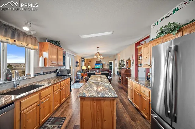 a large kitchen with kitchen island a large counter top space a sink stainless steel appliances and cabinets