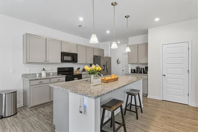 a kitchen with kitchen island granite countertop a stove a sink a center island and cabinets