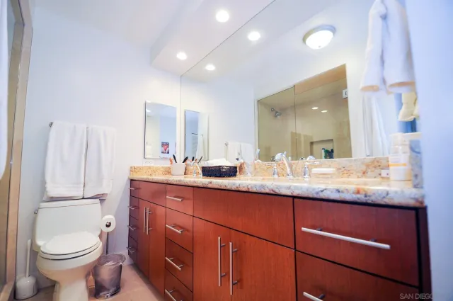 a bathroom with a granite countertop toilet sink and mirror