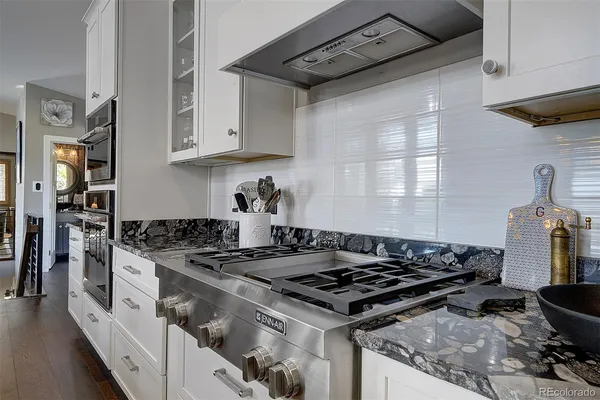 a kitchen with stainless steel appliances granite countertop a stove top oven a dining table and chairs with wooden floor