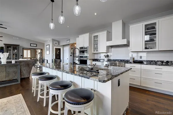 a kitchen with stainless steel appliances granite countertop a dining table chairs stove refrigerator and cabinets