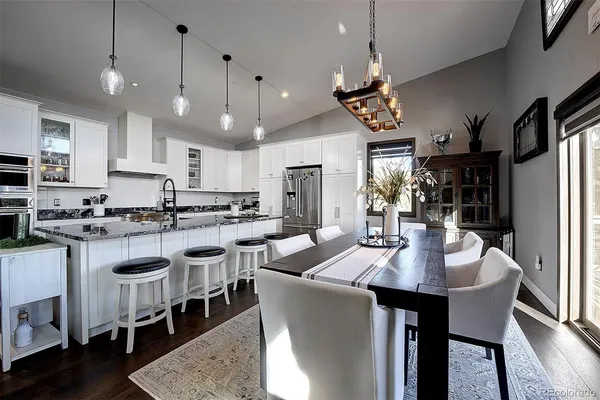 a kitchen with stainless steel appliances kitchen island granite countertop a dining table chairs and a refrigerator